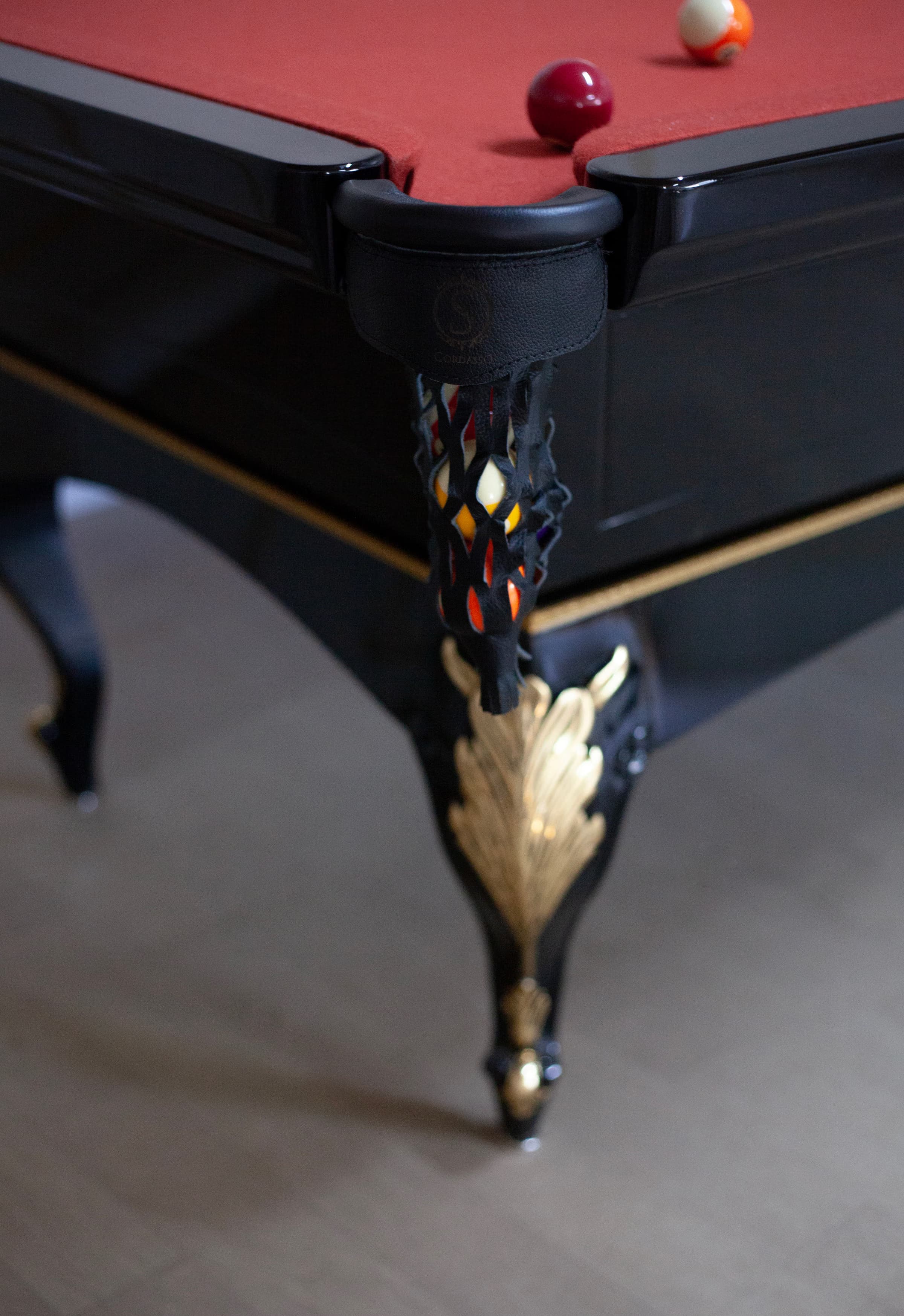 Detalhe da caçapa de couro e pé entalhado em dourado.